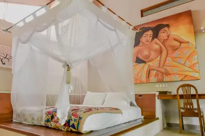a bedroom with a canopy bed with a painting at Ben Bali Villa in Seminyak