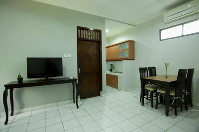 a living room with a dining room table and a television at Sari Indah Cottages in Kuta