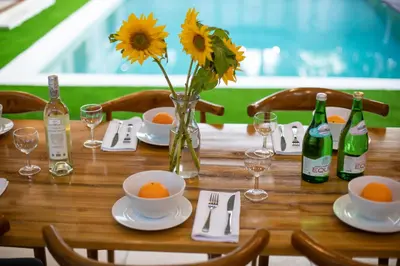 a wooden table with a vase of flowers and wine bottles at Best Location, 9 Bedr Pool Villa, Close To Beach in Seminyak