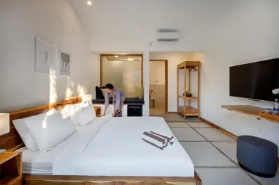 a man standing in a bedroom with a large white bed at Best Location, 9 Bedr Pool Villa, Close To Beach in Seminyak