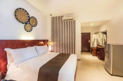 a bedroom with a large bed and a bathroom at Suka Beach Inn in Kuta