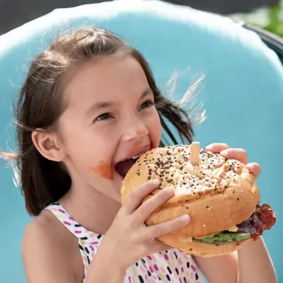 a little girl eating a large hamburger at Holiday Inn Resort Bali Nusa Dua by IHG in Nusa Dua