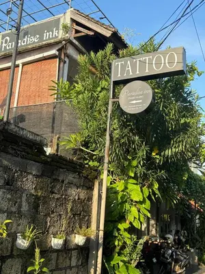 a sign in front of a building with plants at Paradise Inn in Legian