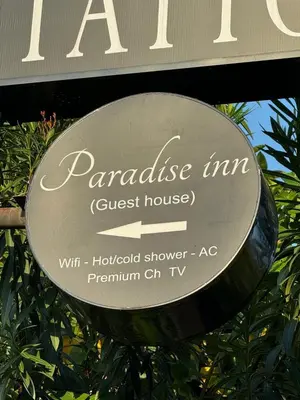 a sign for a parakeet inn guest house at Paradise Inn in Legian