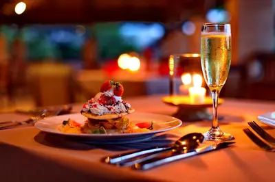 a table with a plate of food and a glass of champagne at Grand Balisani Suites Hotel in Seminyak