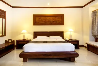 a bedroom with a large bed with two tables and two lamps at Grand Balisani Suites Hotel in Seminyak