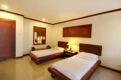 a hotel room with two beds and a mirror at Grand Balisani Suites Hotel in Seminyak