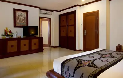 a bedroom with a bed and a flat screen tv at Grand Balisani Suites Hotel in Seminyak