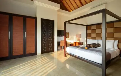 a bedroom with a canopy bed and a desk at The Residence Seminyak in Seminyak
