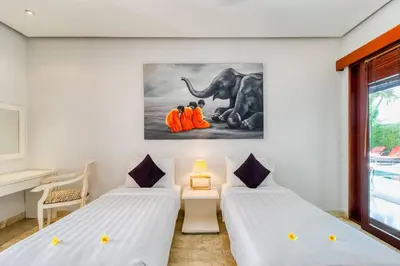 two beds in a room with a painting of an elephant at The Residence Seminyak in Seminyak