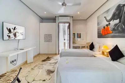 a bedroom with two beds and an elephant painting on the wall at The Residence Seminyak in Seminyak