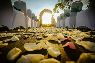 a row of white chairs and a pathway with fallen leaves at Aston Kuta Hotel and Residence in Kuta