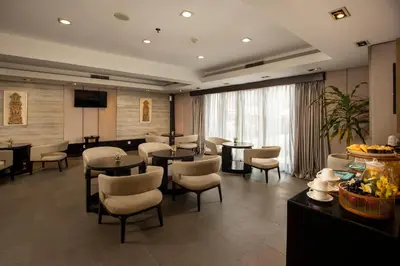 a hotel room with tables and chairs and a television at Away Bali Legian Camakila in Legian