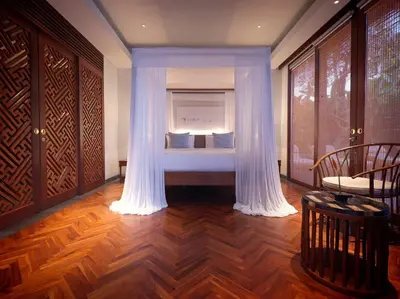 a room with a bed with curtains and a window at The Legian Seminyak, Bali in Seminyak