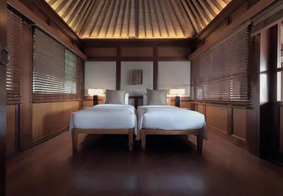 two beds in a room with wooden walls and windows at The Legian Seminyak, Bali in Seminyak