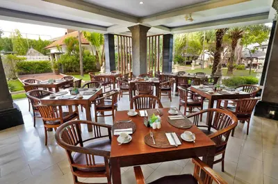 an empty restaurant with wooden tables and chairs at Puri Saron Hotel Seminyak in Seminyak