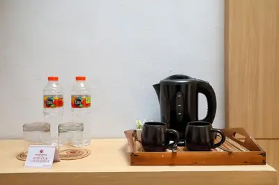 a tray with a coffee maker and two bottles of water at Puri Saron Hotel Seminyak in Seminyak