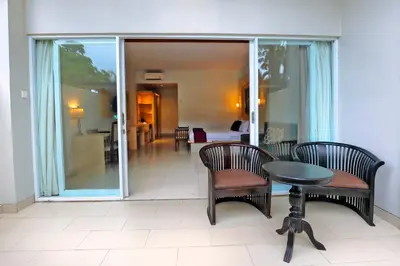 a balcony with chairs and a table and a room at Puri Saron Hotel Seminyak in Seminyak