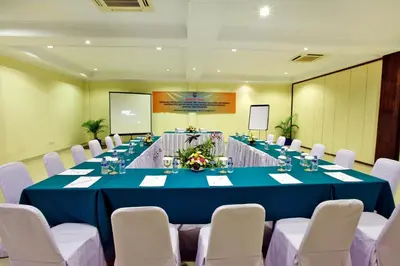 a conference room with a long table with white chairs at Puri Saron Hotel Seminyak in Seminyak