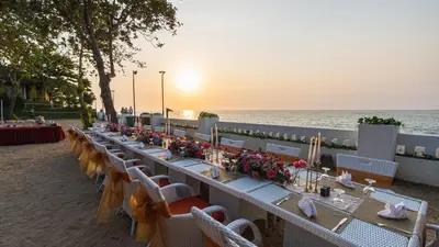 a long table on the beach with chairs and flowers at Discovery Kartika Plaza Hotel in Kuta