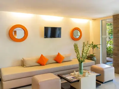 a living room with a couch and a tv on the wall at Discovery Kartika Plaza Hotel in Kuta
