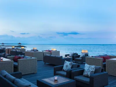 a deck with wicker chairs and tables on the beach at The Royal Santrian in Nusa Dua