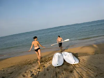 a man and a woman walking on the beach with surfboards at The Royal Santrian in Nusa Dua