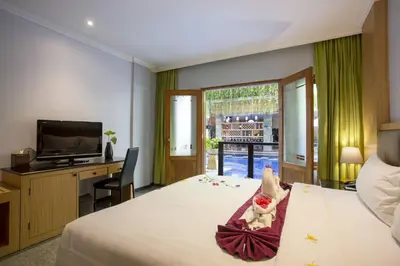 a hotel room with a bed with a tv and a teddy bear at Famous Hotel Kuta Formerly Permata Kuta Hotel in Kuta