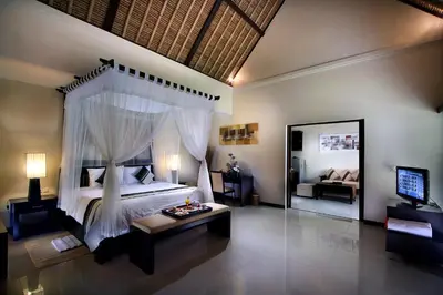 a bedroom with a canopy bed and a living room at Bali Rich Villas in Seminyak