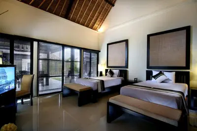 a bedroom with two beds and a flat screen tv at Bali Rich Villas in Seminyak