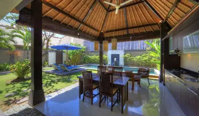 a dining room with a table and chairs under a roof at Bali Rich Villas in Seminyak