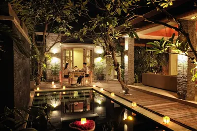 a pool in a house with people sitting at a table at The Wolas Villas in Seminyak