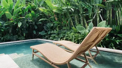 a pair of chairs sitting next to a swimming pool at Aria Exclusive Villas & SPA in Seminyak