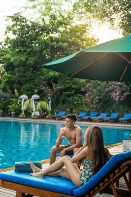 a man and a woman sitting on a beach chair next to a pool at Risata Bali Resort & Spa in Kuta