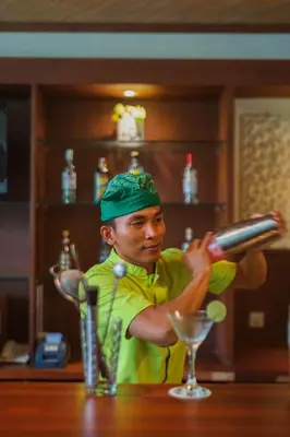 a man is making a drink at a bar at Risata Bali Resort & Spa in Kuta