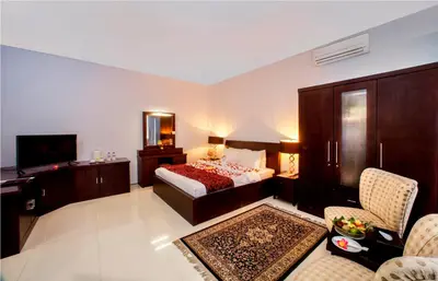 a bedroom with a bed and a desk and a television at The Radiant Hotel in Kuta
