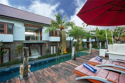 a patio with chairs and an umbrella next to a house at Abi Bali Resort and Villa in Jimbaran