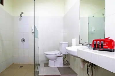 a bathroom with a toilet and a sink and a mirror at RedDoorz at Benesari 2 Legian in Kuta