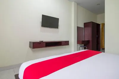 a bedroom with a bed and a tv on a wall at RedDoorz at Benesari 2 Legian in Kuta