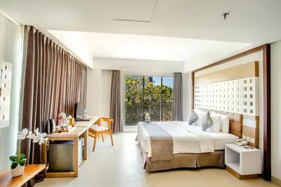 a hotel room with a large bed and a desk at Jimbaran Bay Beach Resort and Spa by Prabhu in Jimbaran