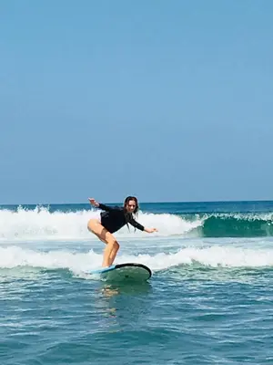 a woman riding a wave on a surfboard in the ocean at Nadialit in Seminyak