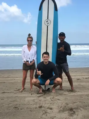 three people standing on the beach with a surfboard at Nadialit in Seminyak
