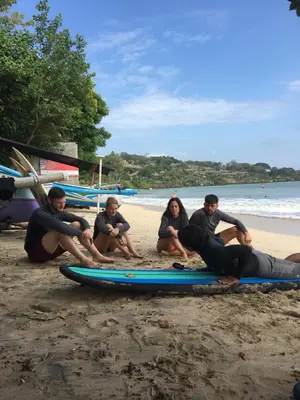 a group of people sitting on surfboards on the beach at Nadialit in Seminyak