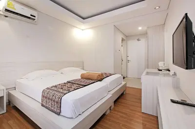a white bedroom with a large bed and a television at Pondok Nyaman 15 in Denpasar