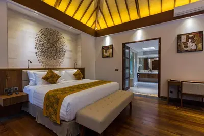 a bedroom with a large bed with a bench in it at Villa Meliya in Canggu