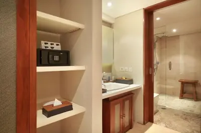 a bathroom with a television and a sink and a shower at The Bandha Hotel & Suites in Legian