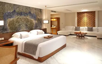 a bedroom with a large bed and a living room at The Bandha Hotel & Suites in Legian