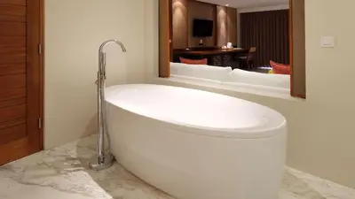 a bath tub in a bathroom with a mirror at The Bandha Hotel & Suites in Legian