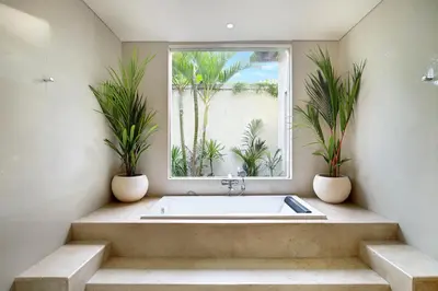 a bathroom with a bath tub with two potted plants at Villa J Deluxe in Canggu