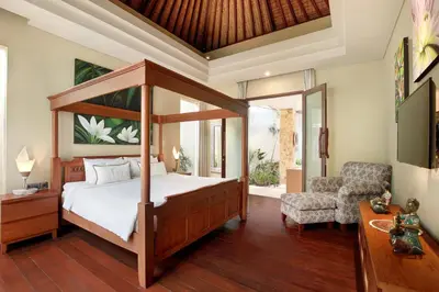 a bedroom with a canopy bed and a chair at Villa J Deluxe in Canggu